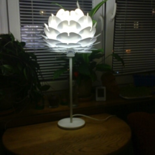 Lampka nocna Zen Mini na białej podstawie w przytulnym pokoju