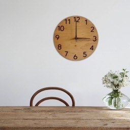 Drewniany zegar ścienny na białej ścianie w pokoju ze stołem krzesłem i wazonem z kwiatami