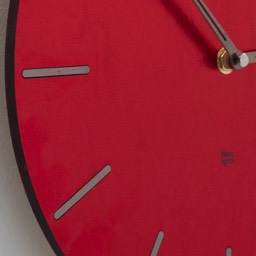 czerwona tarcza zegarowa nowoczesna forma i faktura widoczne wskazówki w kolorze srebrnym oraz logo producenta. Finezyjnie dobrane kolory i precyzyjne wykończenie.