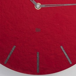 wskazówki nowoczesnego zegara są srebrne a tarcza czerwona znaczniki godzin to proste z zaokrąglonymi końcówkami kreski. Prosty ale wyrafinowany design